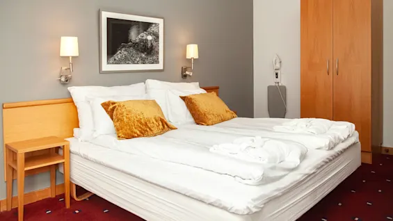 Suite at Home Hotel Bryggeparken, made bed with yellow pillows.