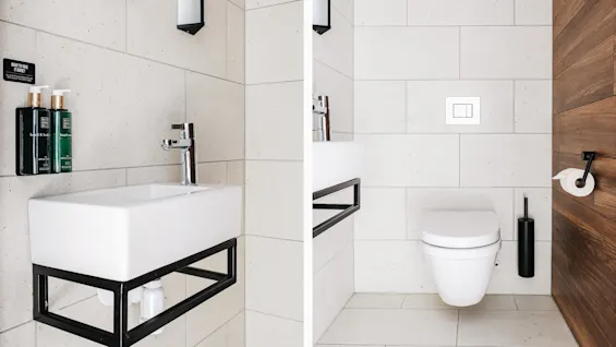 Et lille badeværelse med en hvid vask med sorte beslag og to grønne sæbedispensere ved siden af et vægmonteret toilet og toiletpapirholder. Tekst: "Want to take it home?"