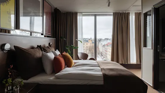 Stratum Suite Clarion Hotel Signissä Tukholmassa. Viihtyisä huone isolla sängyllä, kaupunkinäköalalla ja taideteoksella, jossa lukee Follow the Sun.