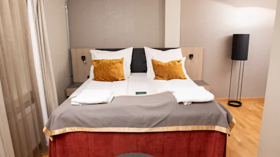 Viihtyisä hotellihuone Home Hotel Bryggeparkenissa siististi pedatulla sängyllä, lämpimällä valaistuksella ja kutsuvalla sisustuksella.