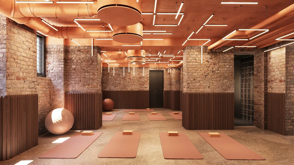 Modern yoga studio with brick walls, warm lighting, and mats laid out on the floor.