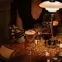 Viihtyisä ilta Hotel Kämp – Kämp Barissa, jossa on erilaisia juomia kuvioidulla pöydällä lämpimässä valaistuksessa.