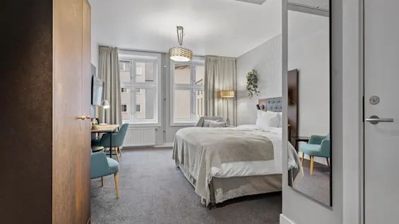 Ett mysigt hotellrum med en bekväm säng, en arbetsplats och naturligt ljus.