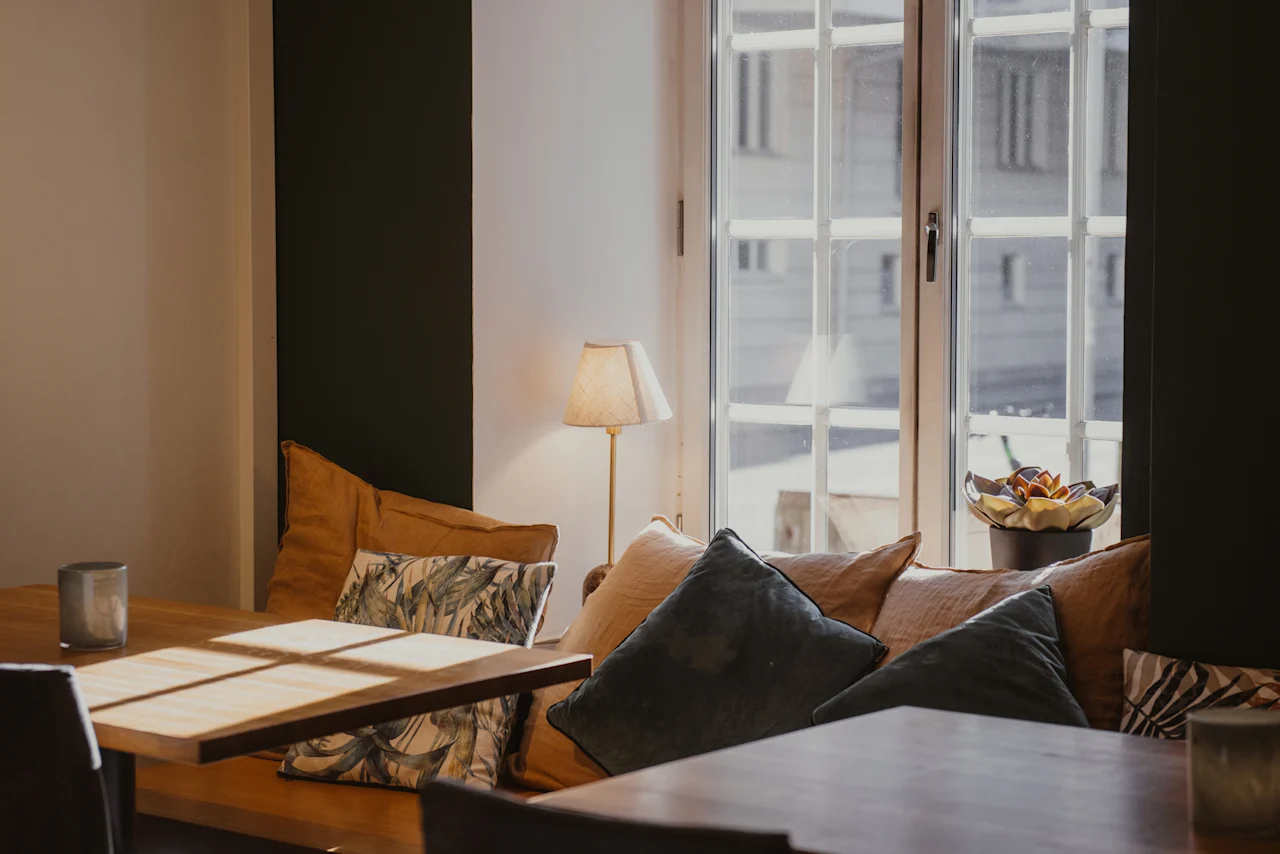 Mysig sittgrupp med träbord och plyschkuddar vid ett solbelyst fönster på Home Hotel Grand, Helsingborg.