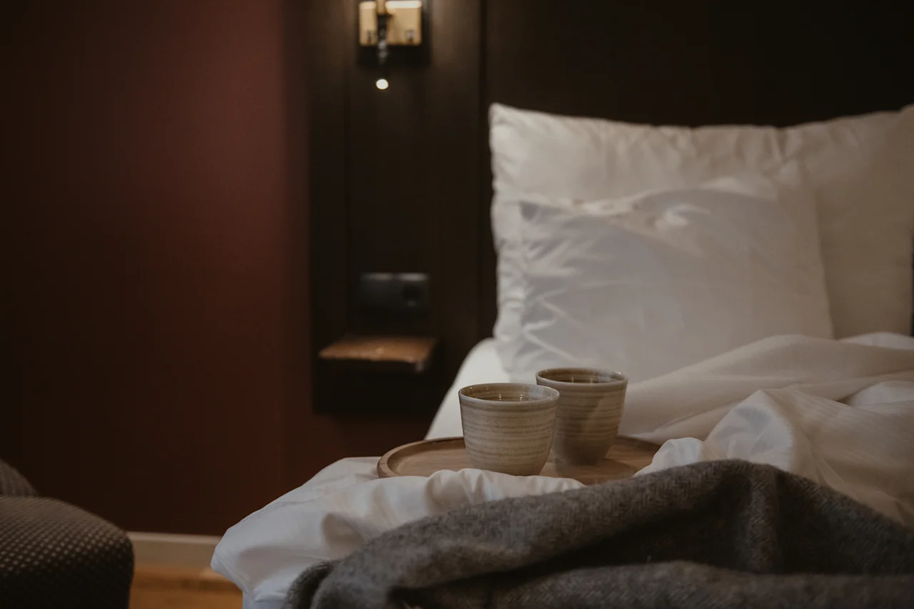 Two cozy cups on a tray on a bed with a blanket, ready for a relaxing moment at Home Hotel Kung Oscar.