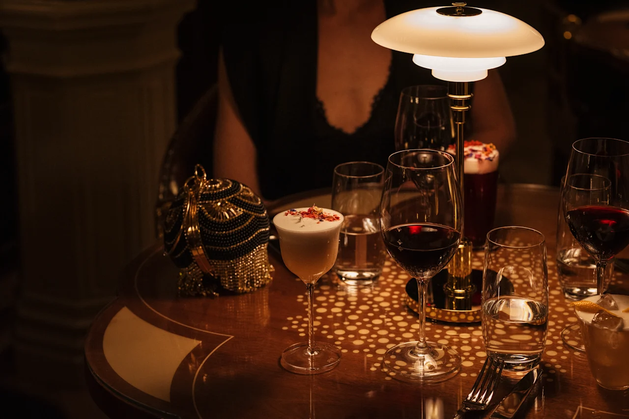 Viihtyisä ilta Hotel Kämp – Kämp Barissa, jossa on erilaisia juomia kuvioidulla pöydällä lämpimässä valaistuksessa.