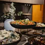 Eloisa buffet, jossa on erilaisia tuoreita salaatteja tummissa kulhoissa, taustalla koristekasvi.