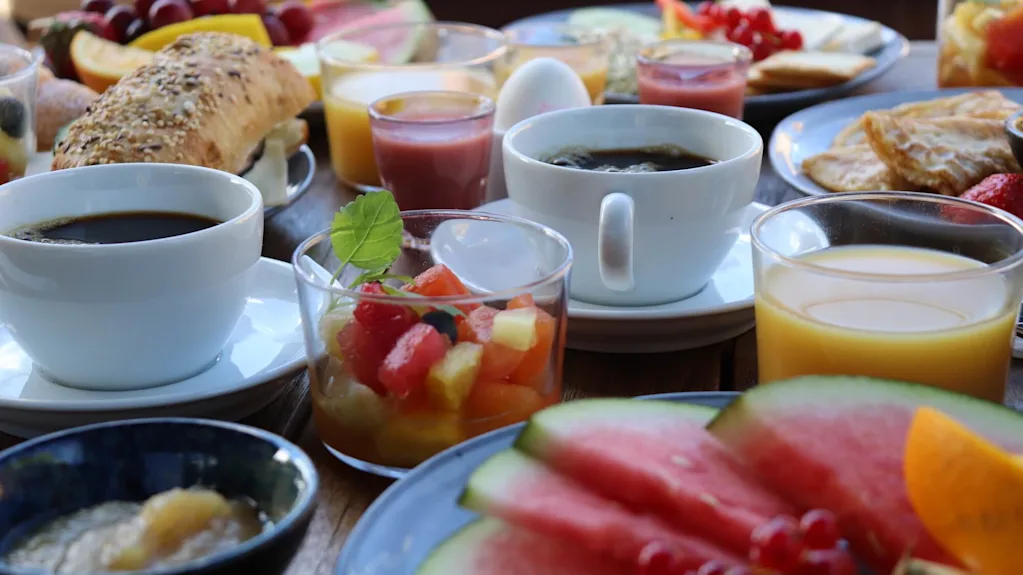 Et utvalg av frokostmat og drikker er presentert på et bord, noe som antyder et felles måltid.