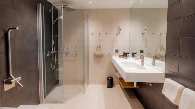 A modern bathroom with a walk-in shower and a double sink vanity, illuminated softly.