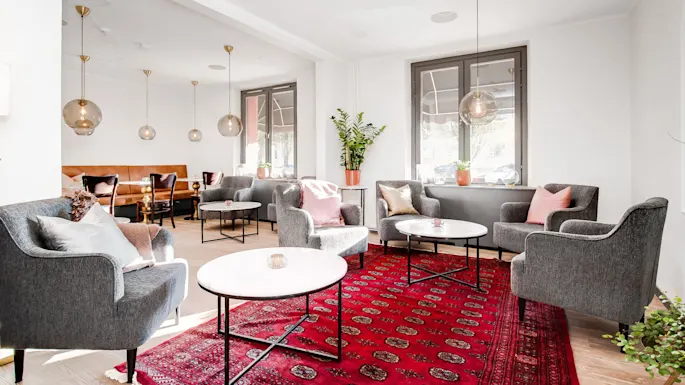A well-lit living room with modern furniture, decorative pendant lights, and a traditional red rug, showcasing a cozy and stylish interior.