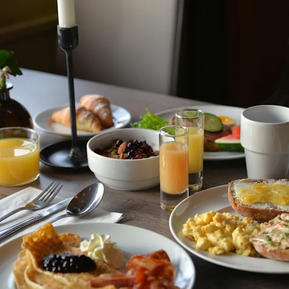 En härlig frukostbuffé på ett träbord med pannkakor, ägröra, juice och bakverk.