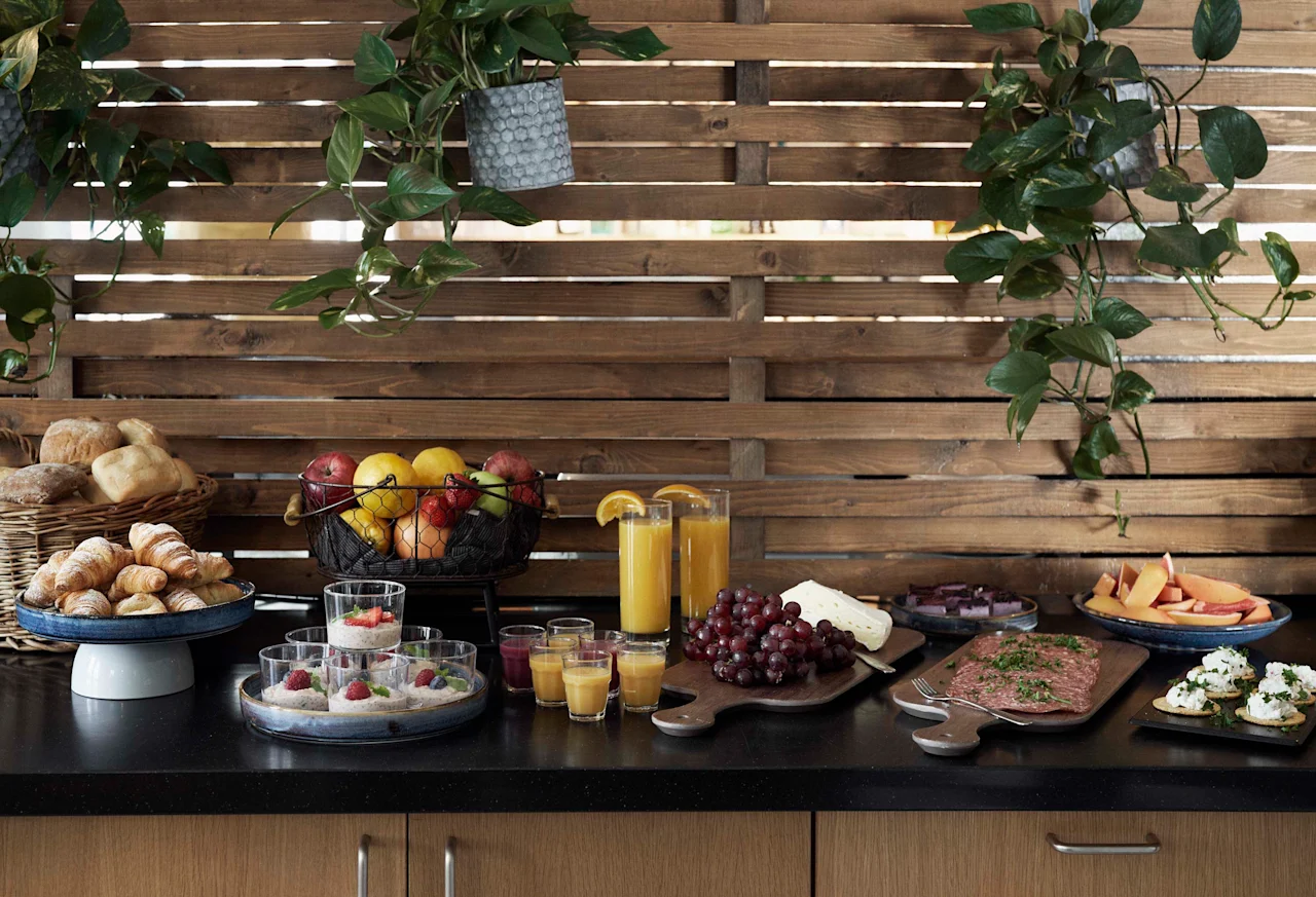 En färgstark buffé med färsk frukt, bakverk, juicer och salta rätter, uppdukad mot en varm träbakgrund.