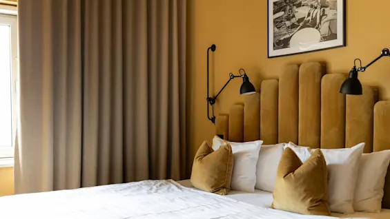 Åh la la! ✨ Et superkoselig hotellrom venter med en komfortabel seng, en stilig sennepsgul sengegavl og et kult innrammet bilde!