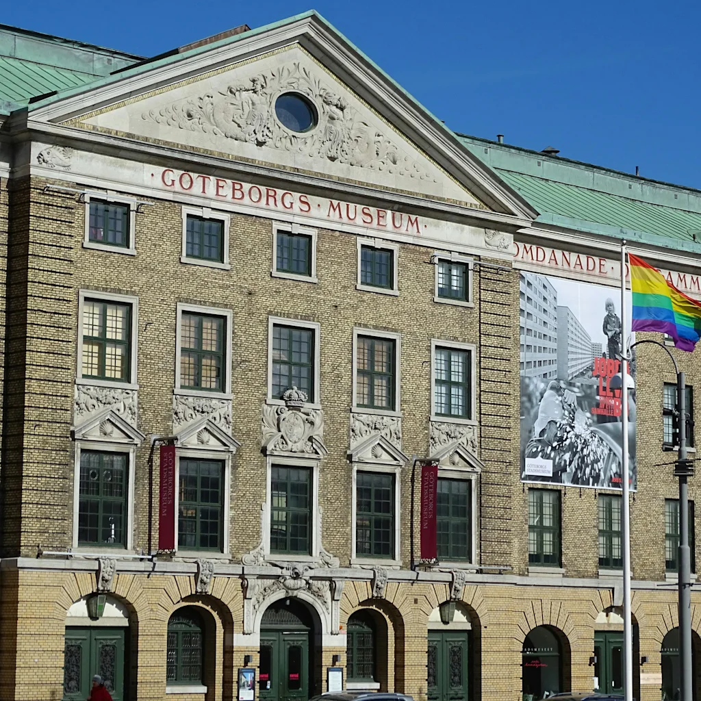 En stor, historisk bygning med teksten 'GOTEBORGS MUSEUM', med bannere og et regnbueflag, der vajer stolt.