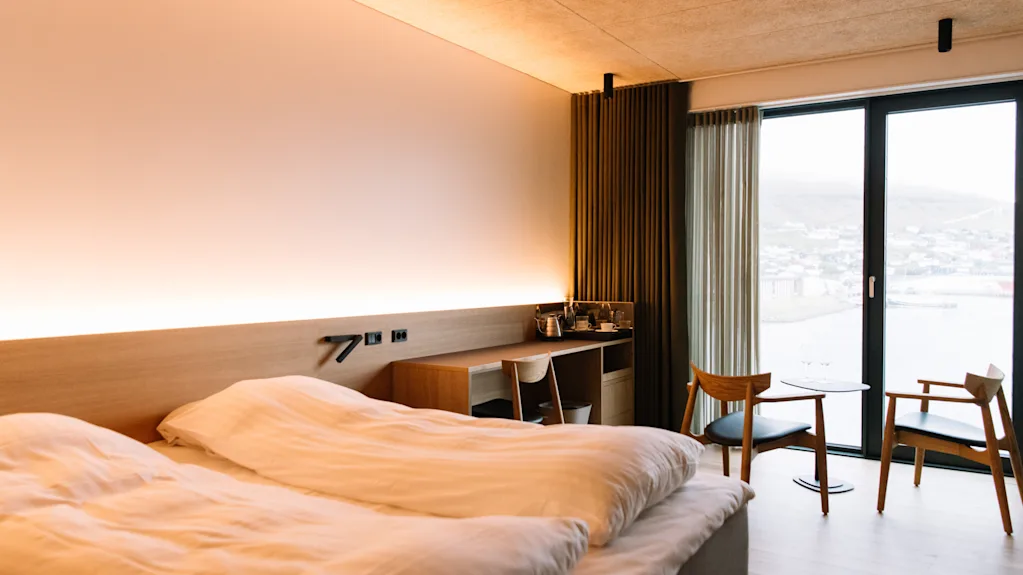 Moderni hotellihuone KG Hotel på Färöarna -hotellissa, jossa on parivuode, puukalusteet ja suuret maisemaikkunat.