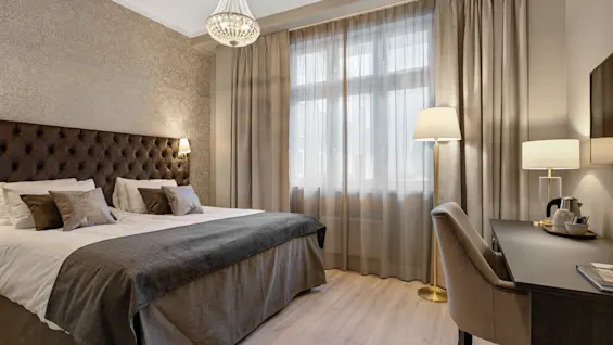 Et hyggeligt hotelværelse med en stor seng, et skrivebordsområde og blød belysning, ideelt til afslapning eller arbejde.