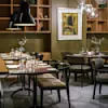 En mysig modern restaurang med snyggt dukade bord, mjuk belysning och elegant dekor. Varmt trä och stiliga möbler skapar en inbjudande atmosfär, perfekt för en trevlig måltid.
