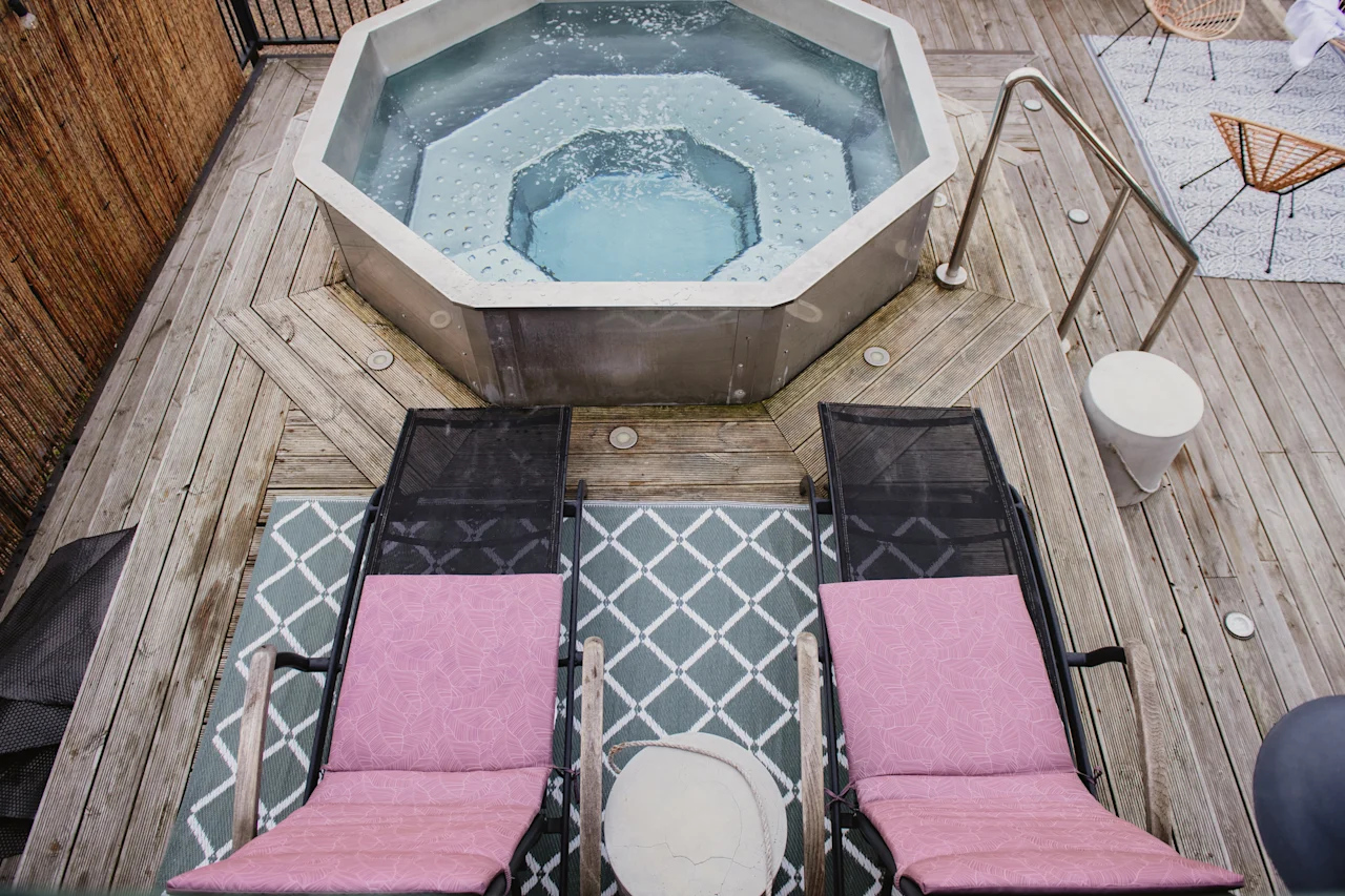 An inviting outdoor hot tub area with two lounge chairs on a wooden deck, perfect for relaxation.