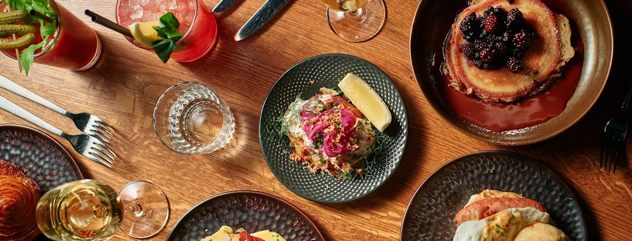 En härlig brunchupplevelse på Clarion Hotel Post med pannkakor, croissanter och cocktails på ett träbord.