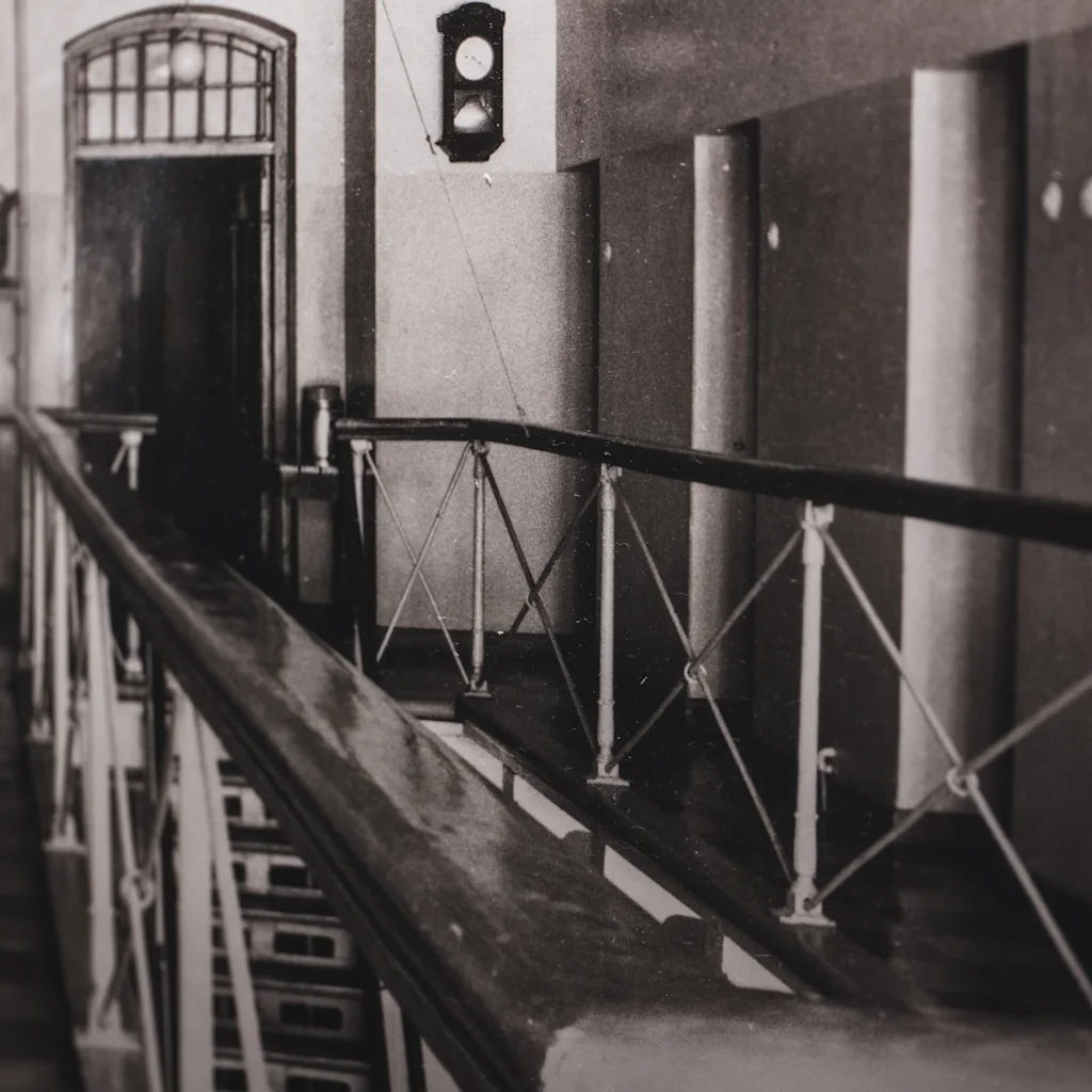 En svartvit bild av en fängelsekorridor med räcke, som visar Home Hotel Bilans historiska utseende som fängelse.
