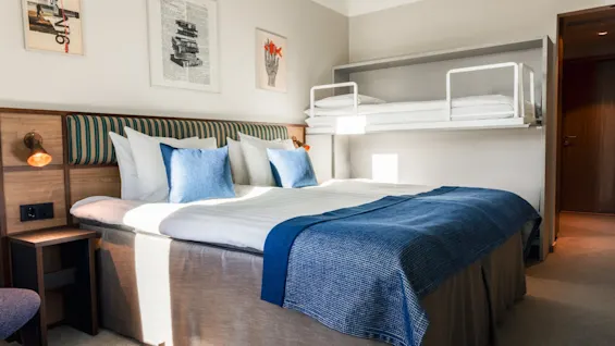 A cozy hotel room at Quality Hotel The Book featuring a large bed with blue accents and a convenient bunk bed above.