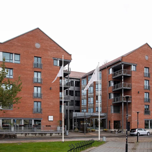 A modern brick hotel building with balconies and large windows, featuring a prominent "HOTEL" sign.