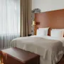 Et koselig hotellrom med en stor seng, sengegavl i tre og myk belysning, klart for et komfortabelt opphold.