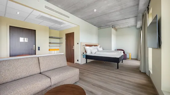 An inviting hotel room featuring a cozy living space with a sofa and a separate sleeping area with a bed.