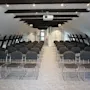 Ett modernt konferensrum med rader av stolar, en projektor och synliga takbjälkar, redo för en presentation.