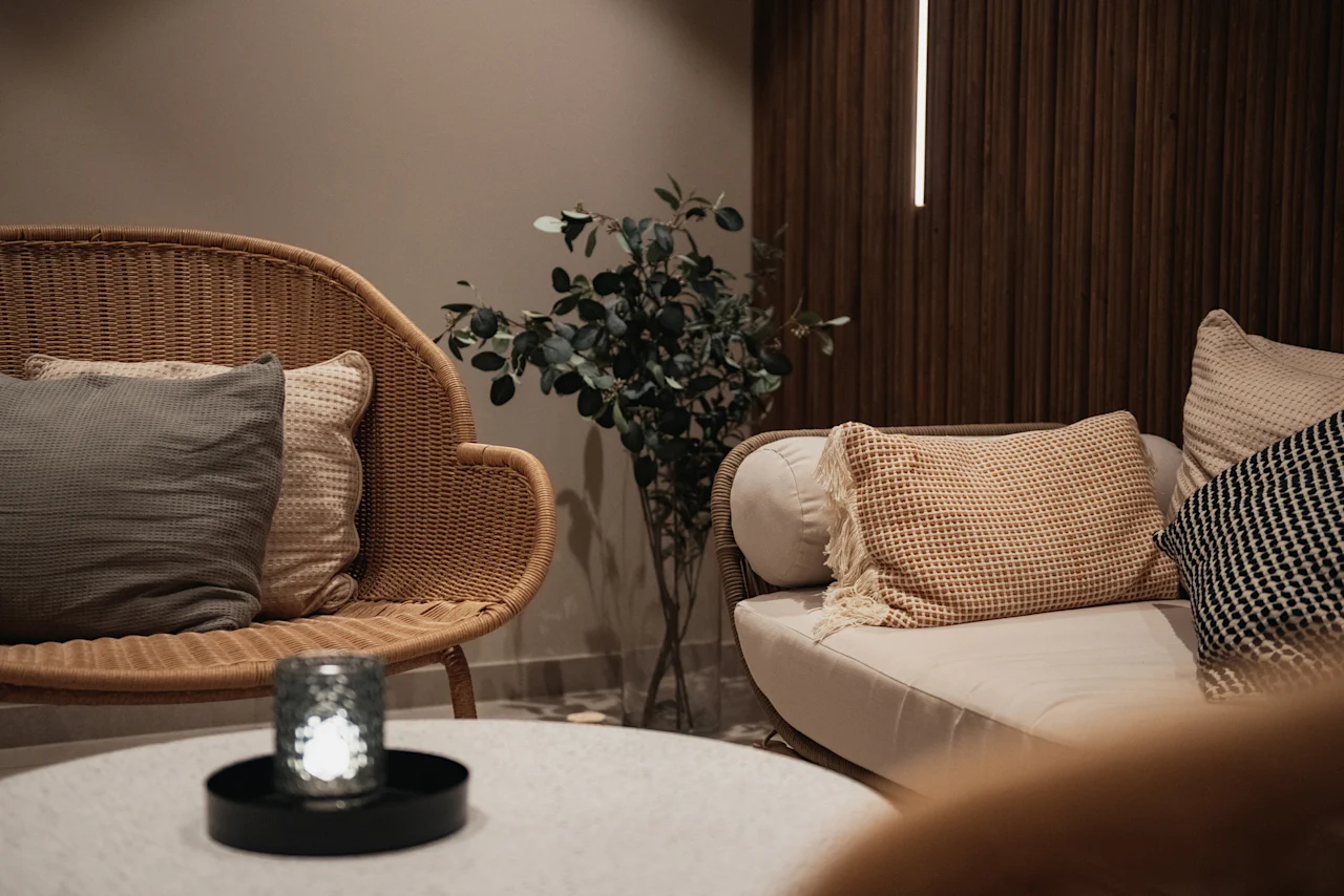 A cozy seating area at Home Hotel Uppsala with comfortable chairs, cushions, a plant, and a lit candle on a table.