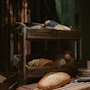 Rustiikkinen leipänäyttely, jossa on erilaisia leipiä ja sämpylöitä puuhyllyillä ja leikkuulauta veitsen kanssa.