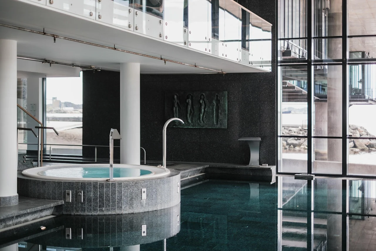 Indoor pool and hot tub at Farris Bad in Larvik, with large windows overlooking the sea and a modern, spacious design.
