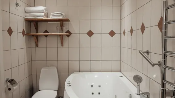 Et koselig bad på Home Hotel Norre Park i Halmstad, med toalett, boblebad og hyller med friske håndklær.