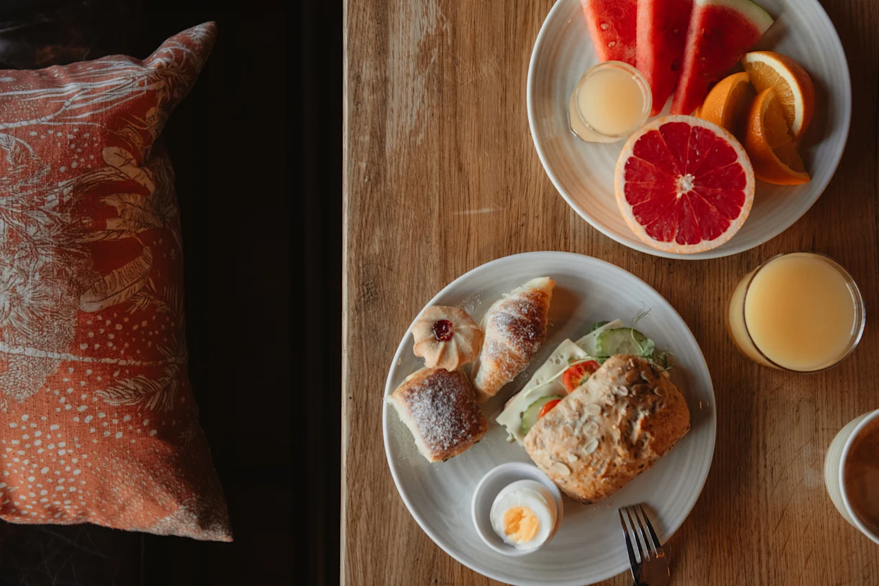 En härlig frukostbuffé med färsk frukt, bakverk och en smörgås på ett träbord på Home Hotel Grand, Helsingborg.