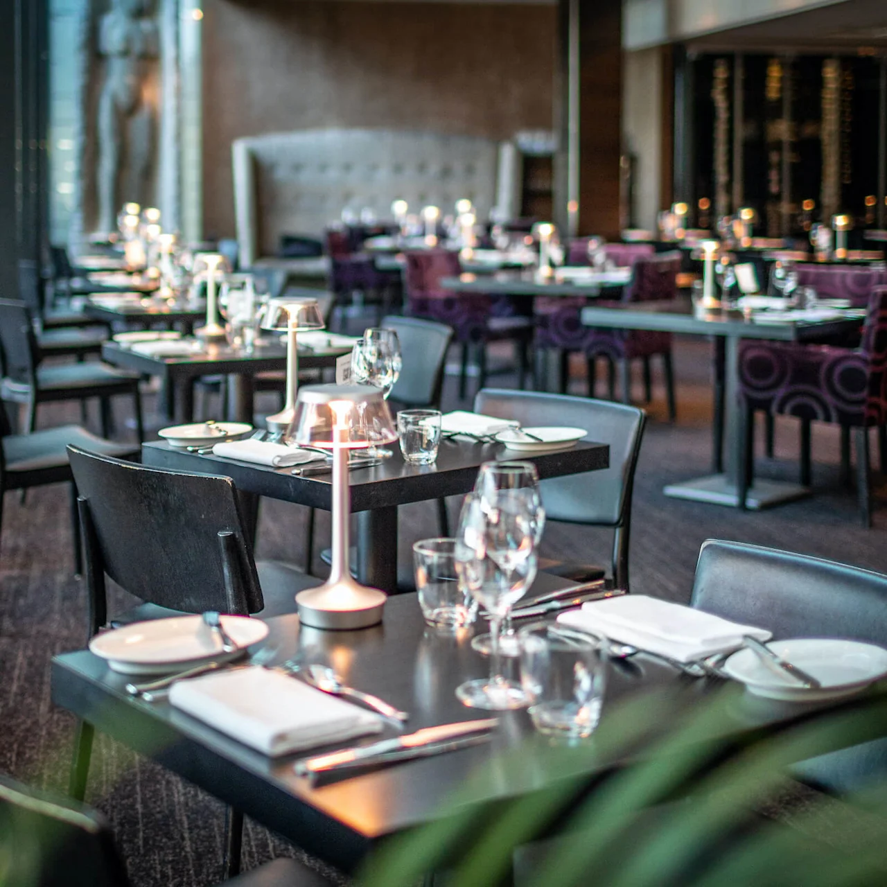 En elegant opdækket restaurant med borde, stole og bordtøj, klar til gæster.