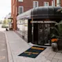 Inngang til Comfort Hotel Sundsvall med sort markise og potteplanter; en velkomstmatte har påskriften "WELCOME COMFORT HOTEL."