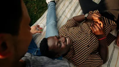 Kille ligger på en gräsmatta och ler. 
