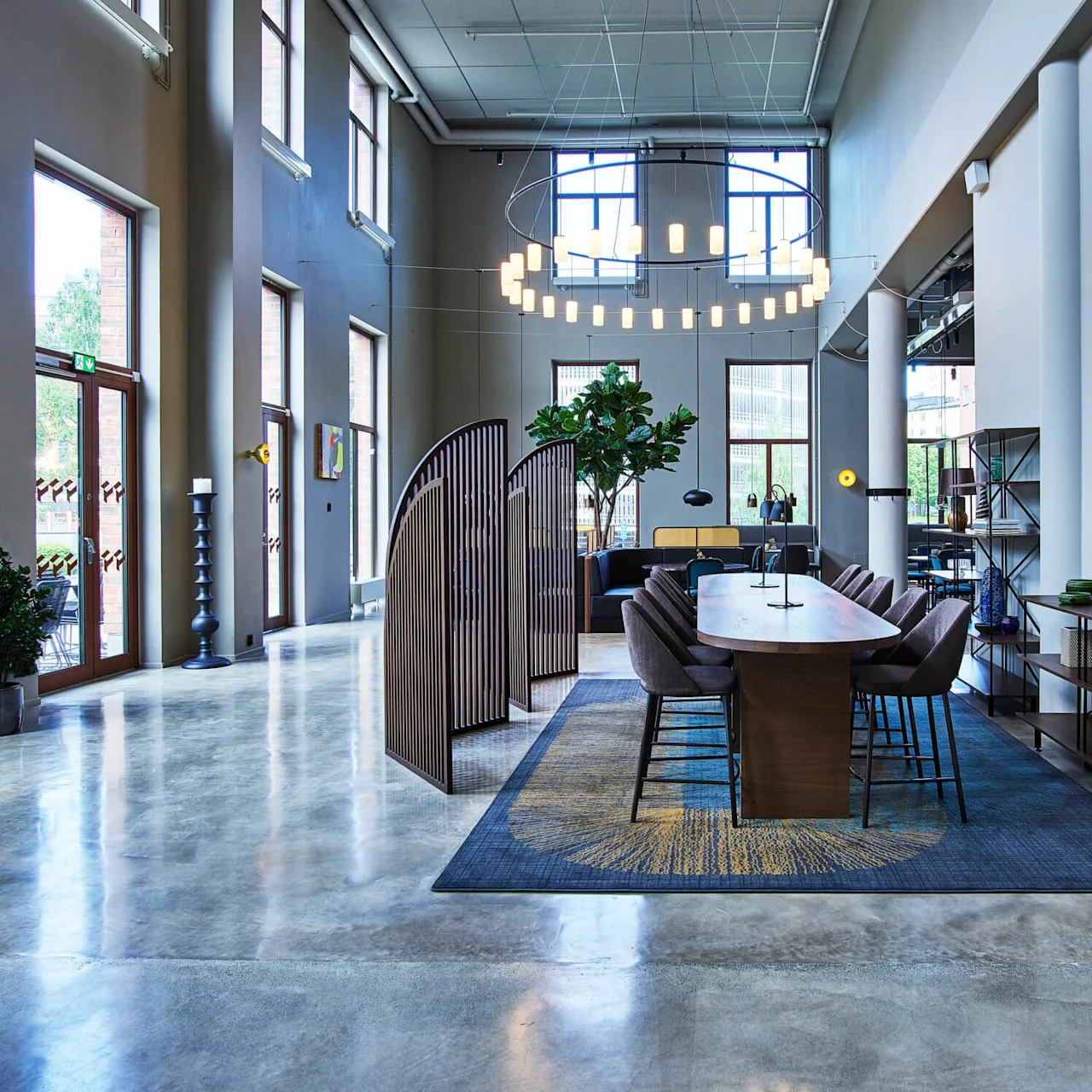 An office lobby with a modern design, polished floors, furnishings, and indoor plants, illuminated by natural and artificial light.