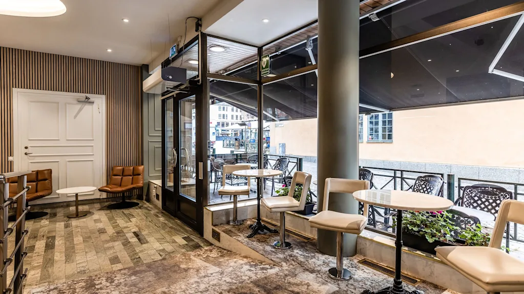 Viihtyisä sisätilojen oleskelualue, joka johtaa ulkoterassille kahvilapöytineen Comfort Hotel Linköping Cityssä.