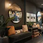 Et hyggeligt og stilfuldt hotelloungeområde med mørke vægge, komfortable sofaer, dekorative planter, spejle og indrammet kunst.