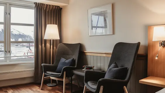 A cozy room with two armchairs by a window overlooking a snowy mountain landscape, perfect for relaxation.