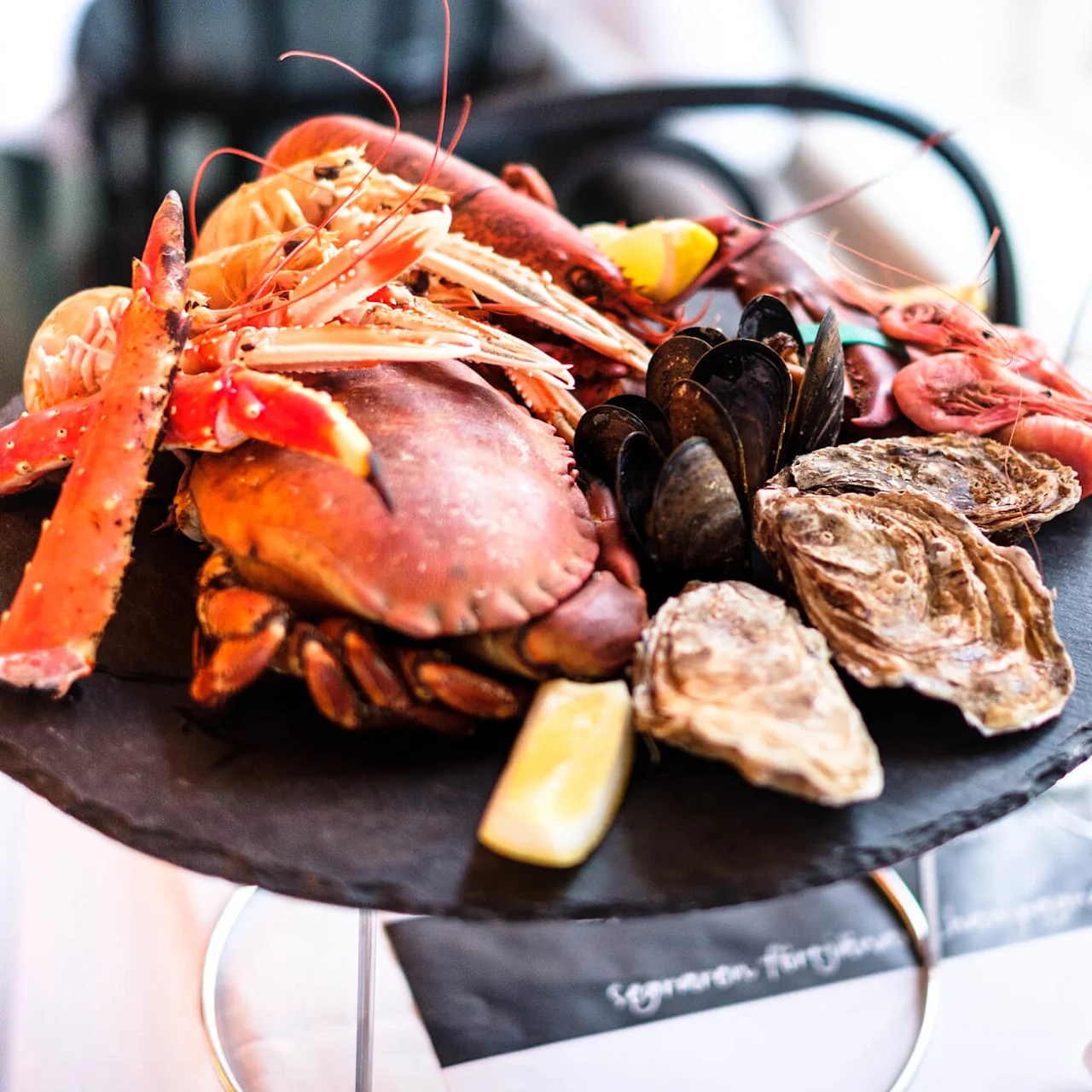 A variety of seafood on a platter, elegantly presented on a table with wine glasses.