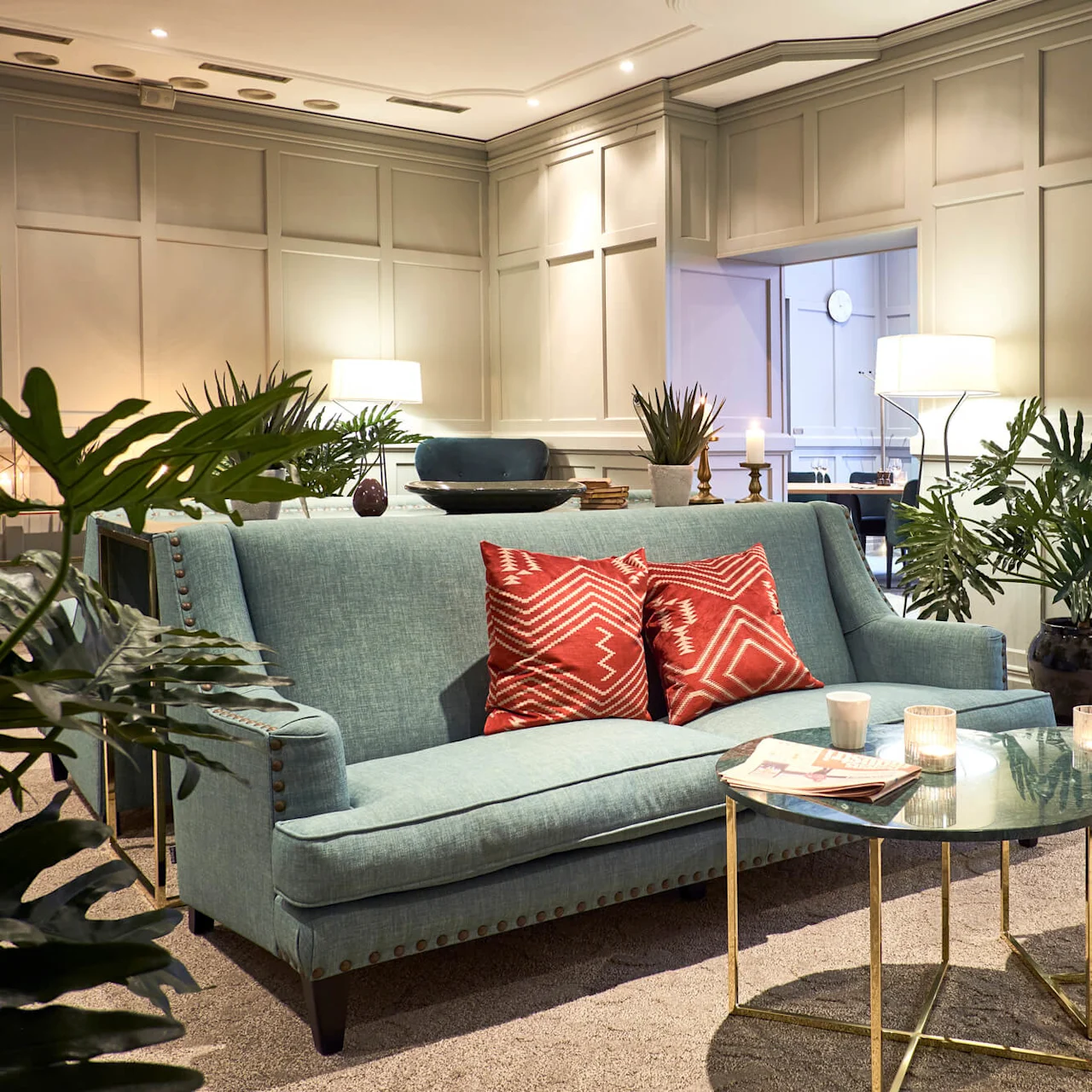 A teal sofa with patterned cushions, adorned with a side table, in an elegant living room.