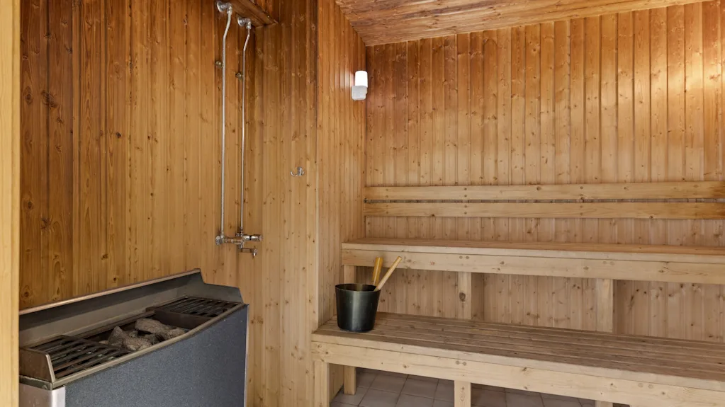 En koselig trebadstue med benker, en ovn og en dusj, som inviterer til avslapning og varme.