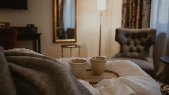 A tranquil scene in a hotel room, featuring warm drinks on a bed, perfect for a relaxing stay at Home Hotel Kung Oscar.