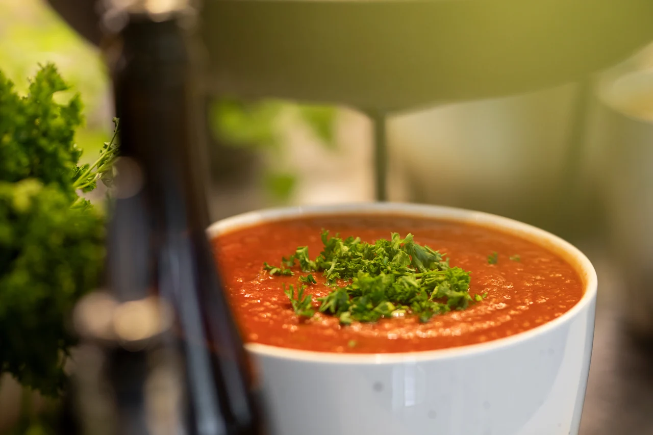En skål med livlig röd soppa, garnerad med färska gröna örter, redo att serveras.