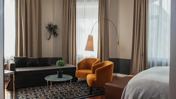 Et indbydende hotelværelse med et komfortabelt loungeområde, komplet med en sofa, to lænestole og blød belysning.