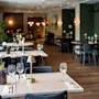 Tastefully set dining tables with wine glasses and small lamps in an elegant restaurant, featuring ambient lighting and dark, modern decor creating a warm, inviting atmosphere.