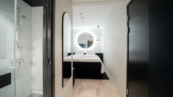 Et moderne hotellrom på Quality Hotel Strawberry Arena med et elegant dusjområde og en seng med et glødende sirkulært speil.