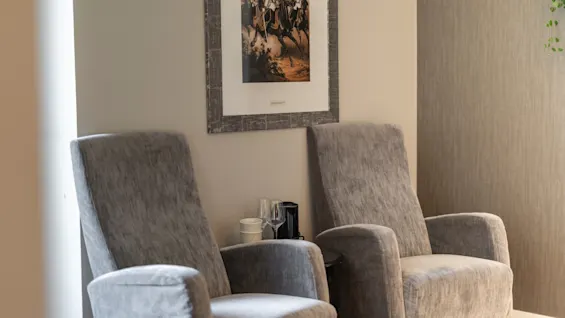 En inbjudande hotellounge med två bekväma fåtöljer och en klassisk målning, perfekt för en stunds vila.